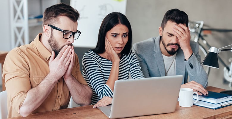 3 shocked people looking at laptop