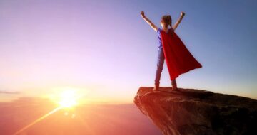 Superhero girl at top of mountain